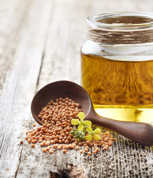 Mustard oil with seeds on wooden background