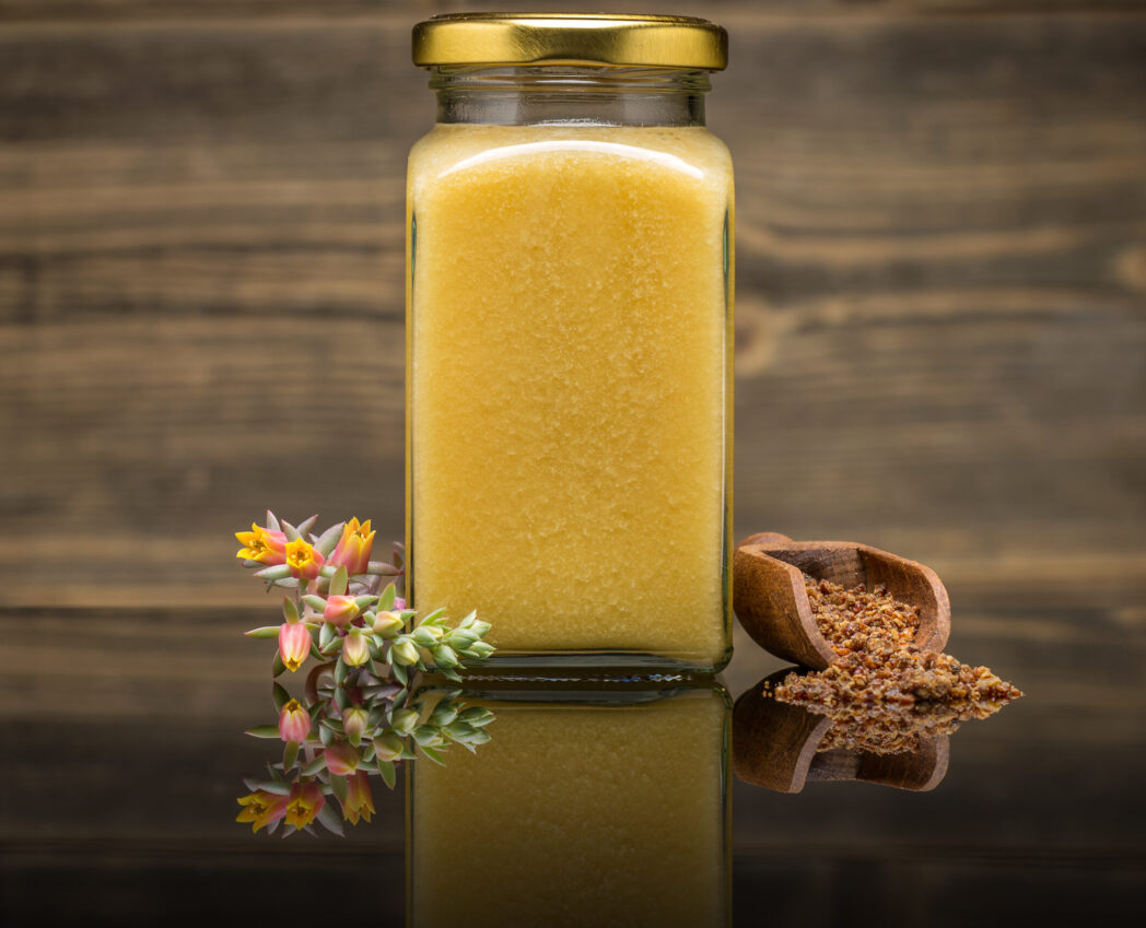 Honey in jar and bee pollen in wooden scoop